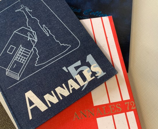 Copies of the Utica College 1951, 1972 and 1993 yearbooks stacked atop each other on a desk.