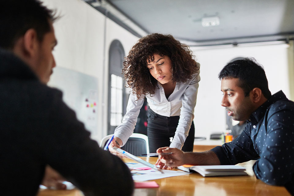 Female data analyst discussing insights with colleagues in a meeting room.