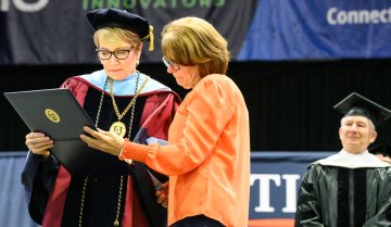 Valerie Fadigan accepts degree forher nephew, John Paul 'JP' Ramel.