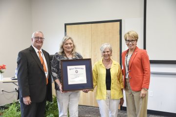 Provost Todd Pfannestiel, Leslie Corbo holding the Zimpel Endowed Professorship Award, award founder Fredericka 'Fritzie' Paine, and President Laura Casamento stand in a row.