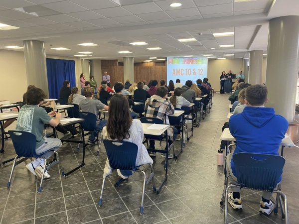 High school students sit in chairs facing a screen in the Concourse for the AMC 10 and AMC 12 Mathematics Competition.